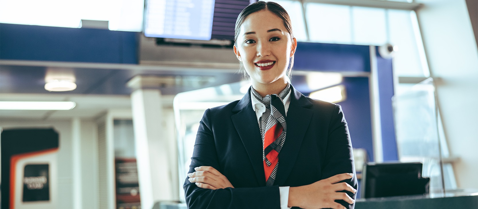 A airline employee smiling, looking at camera with her arms crossed