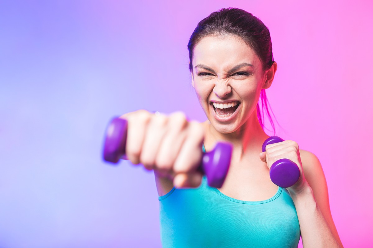 young woman exercises andpunches with dumbell AdobeStock_259041090