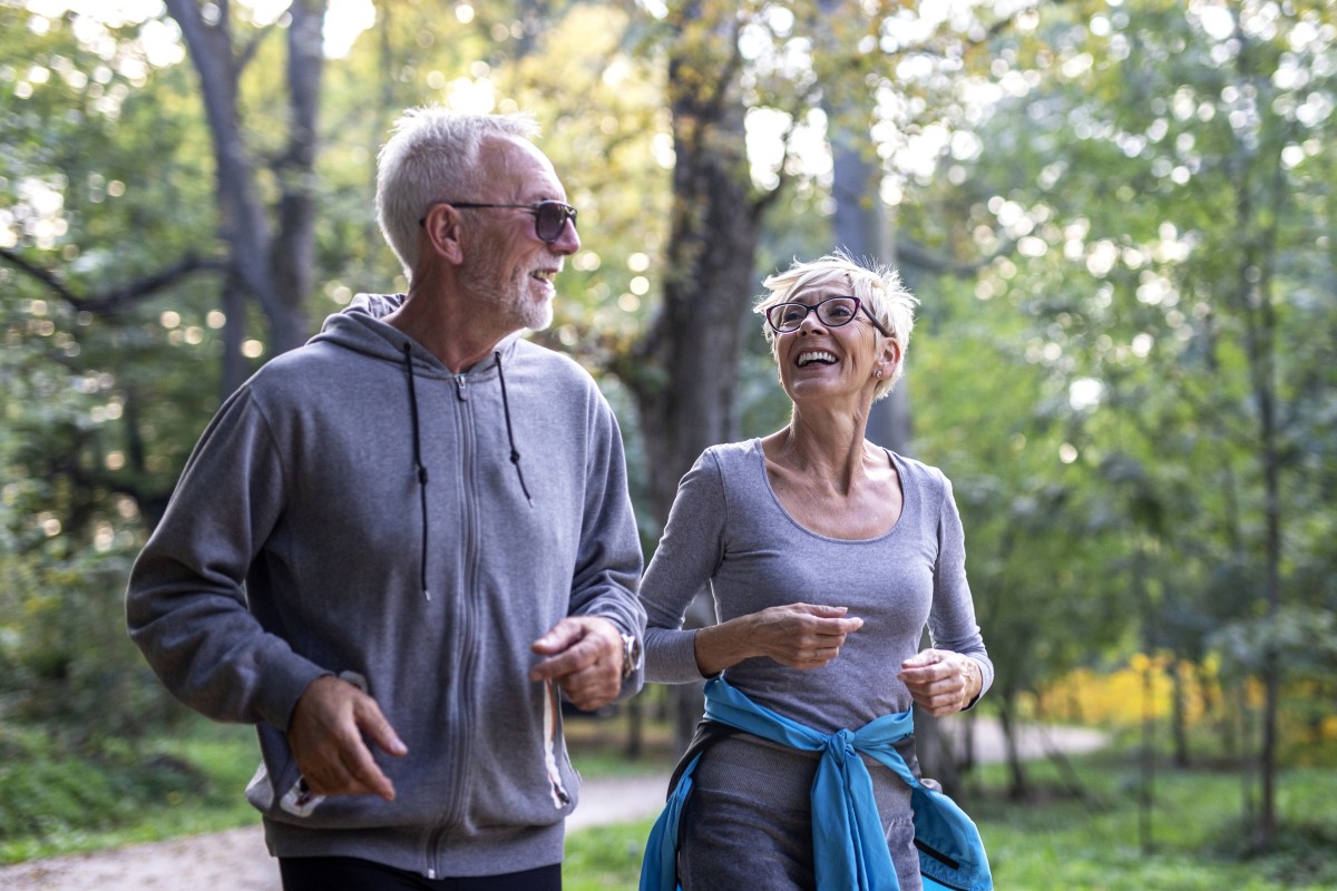 Older white man and woman walk on a paved wooded trail copy