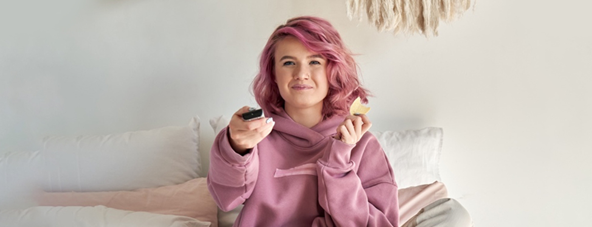 Young woman eating snack and watching tv