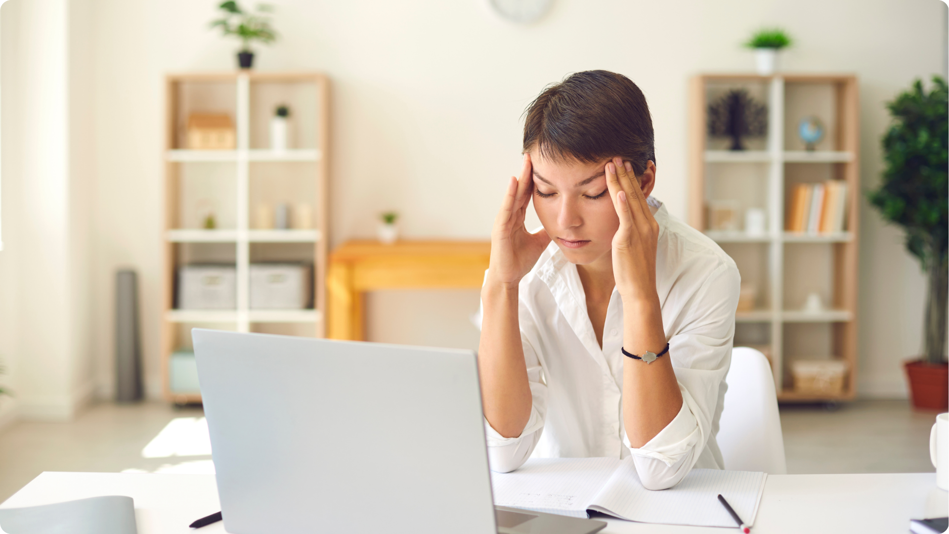 Migraine awareness Month A person holding their head because they have a migraine in front of their computer