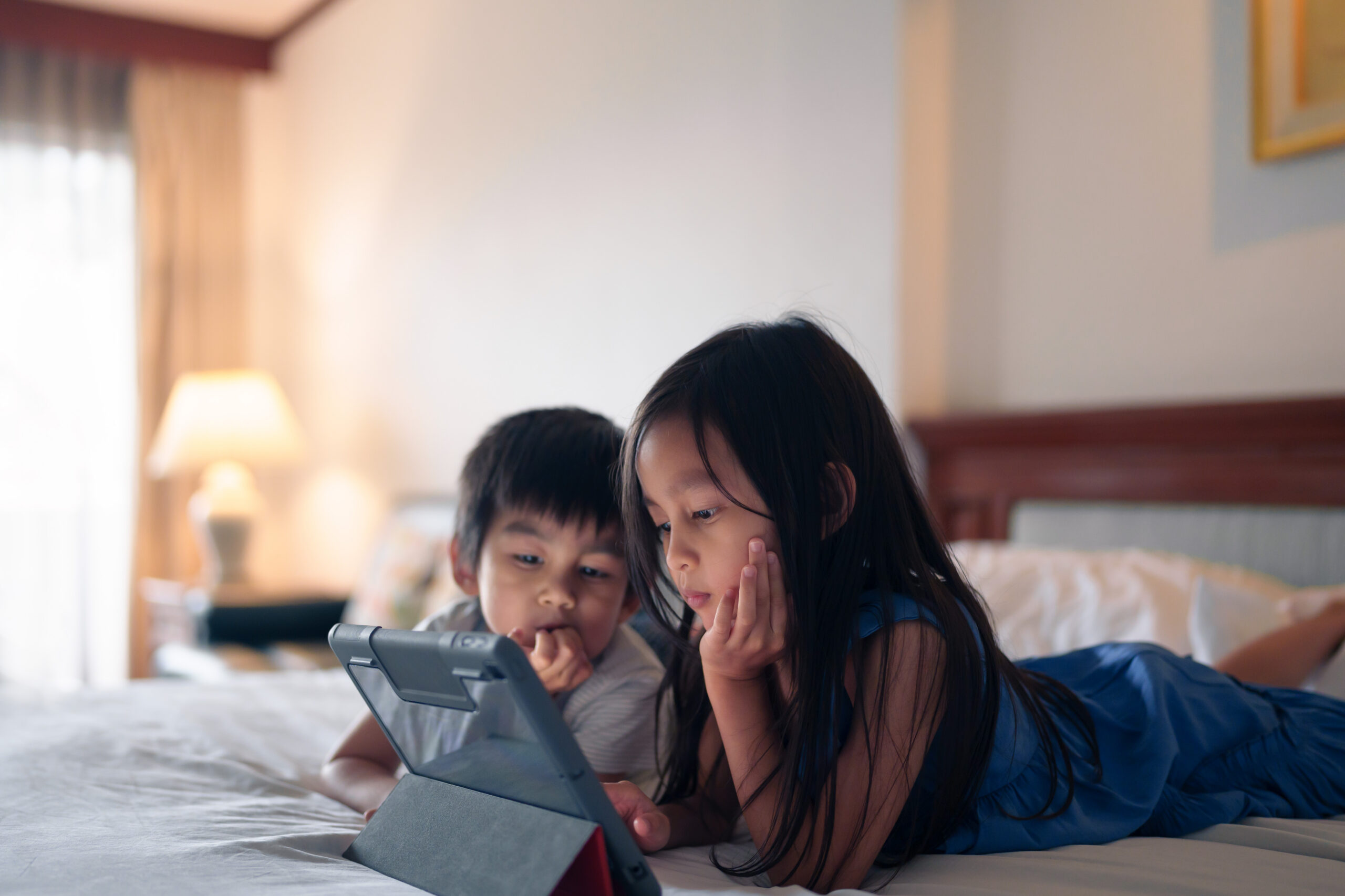 Fraterie qui regarde un ipad sur le lit Fraterie qui regarde un ipad sur le lit